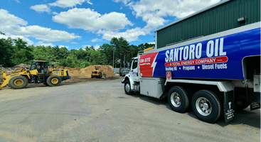 Santoro Oil delivering oil to a commercial customer with yellow iron in the distance