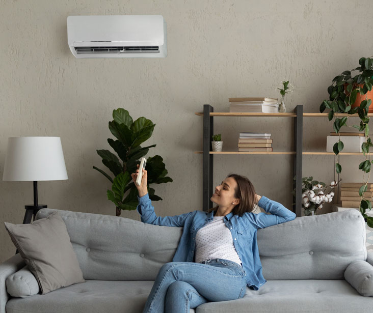 A woman enjoys cool air from a ductless mini-split air conditioner
