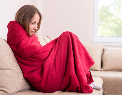 A woman wrapped up in a blanket considering calling Santoro for Emergency Heating Service